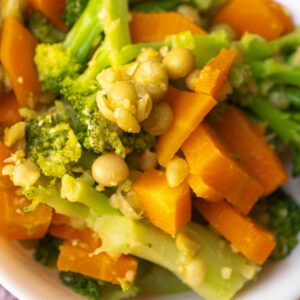 Colorful mix of steamed carrots, broccoli, and peas in a white bowl.